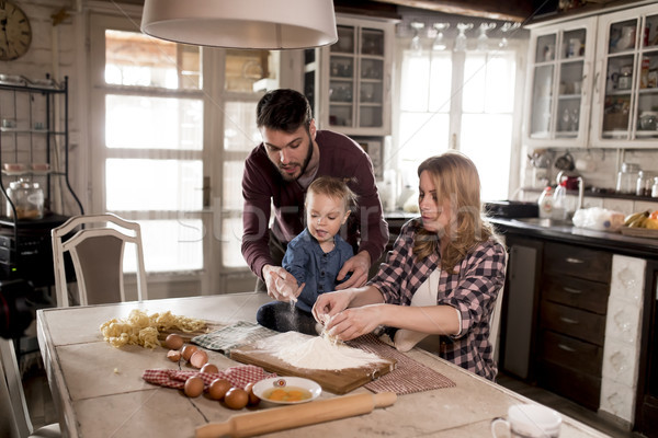 Happy family making pasta in the kitchen at home Stock photo © boggy