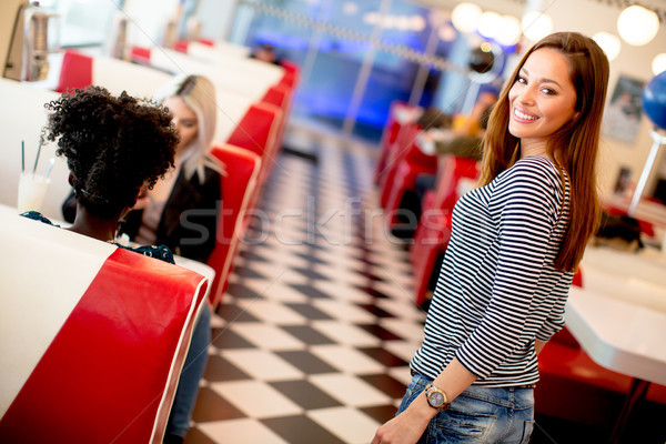 Multiracial female friends eating fast food at a table in the di Stock photo © boggy