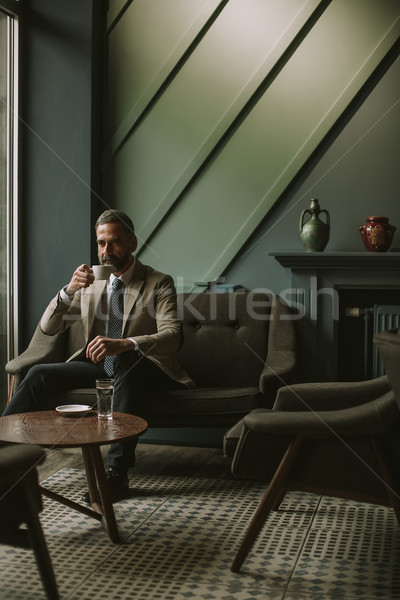 Handsome senior businessman drinking coffee and using mobile pho Stock photo © boggy