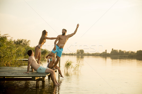Group of young people having fun on pier at the lake Stock photo © boggy