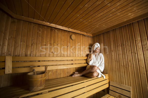 Young woman wrapped in a white towel relaxing in wooden sauna ro Stock photo © boggy