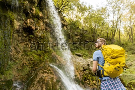 Young hiker stopped beside a mountain waterfall to rest Stock photo © boggy