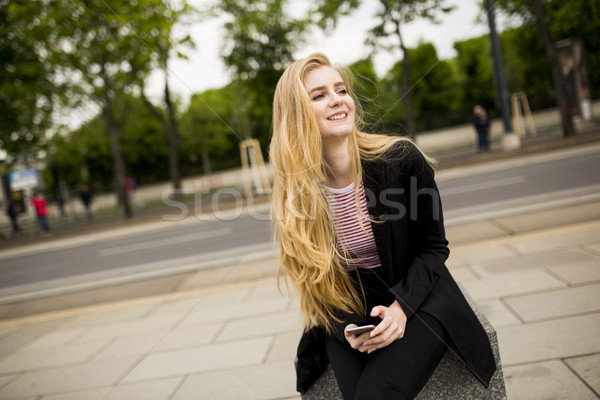 Cute young woman on the street with mobile phone Stock photo © boggy