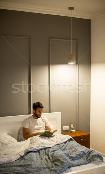 Young Man Reading Book In Bed Stock Photo C Goran Bogicevic