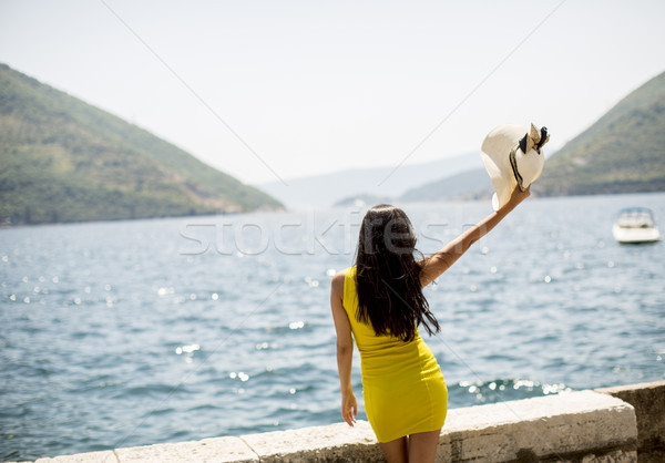 Young attractive woman with a hat poses by the sea at sunny day Stock photo © boggy