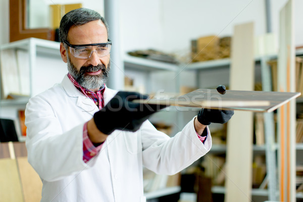 Handsome mature engineer testing colors on wooden specimens Stock photo © boggy