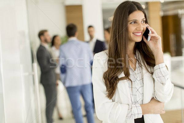 Businesswoman on phone call with colleagues in background at off Stock photo © boggy