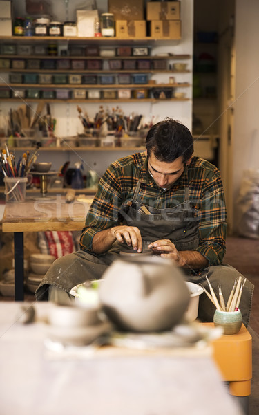 Male artist makes clay pottery on a spin wheel Stock photo © boggy