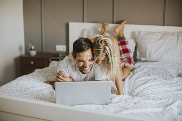 Meghitt szerelmespár laptopot használ ágy hálószoba mosoly Stock fotó © boggy