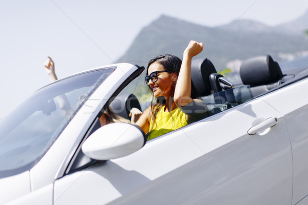 Young women in white cabriolet car driving everywhere and lookin Stock photo © boggy