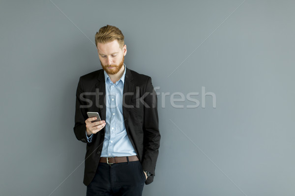 Redhair man using mobile phone standing by the wall Stock photo © boggy