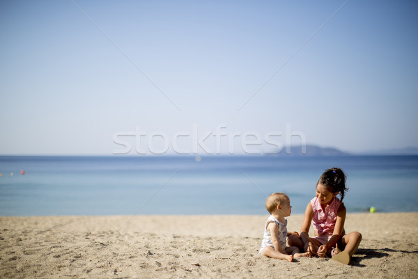 Cute little sisters sitting on a beach Stock photo © boggy