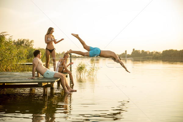 Group of young people having fun on pier at the lake Stock photo © boggy