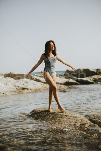 Pretty young woman on the stony shore Stock photo © boggy