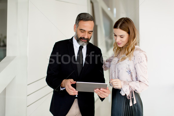 Middle-aged businessman and young businesswoman with tablet in o Stock photo © boggy