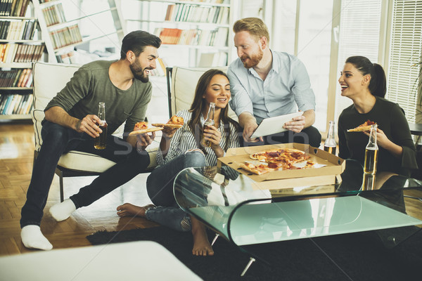Young people eating pizza and drinking cider in the room Stock photo © boggy