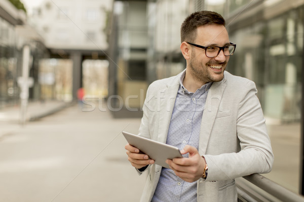 Young businessman with digital tablet by the office building Stock photo © boggy