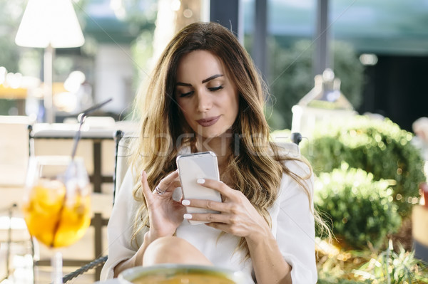 Attractive young woman sitting in restaurant and using mobile ph Stock photo © boggy