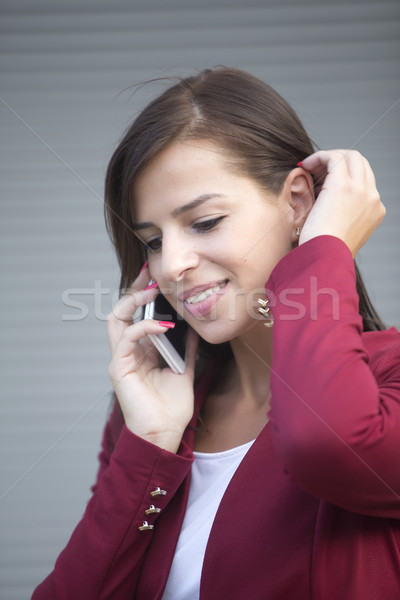 Fiatal üzletasszony piros blézer beszél mobiltelefon Stock fotó © boggy