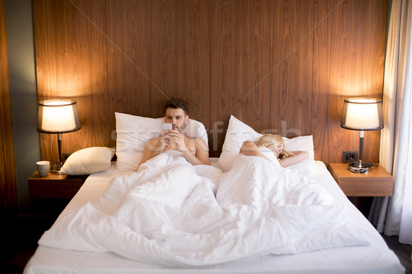 Young man looking at phone while woman sleeping Stock photo © boggy