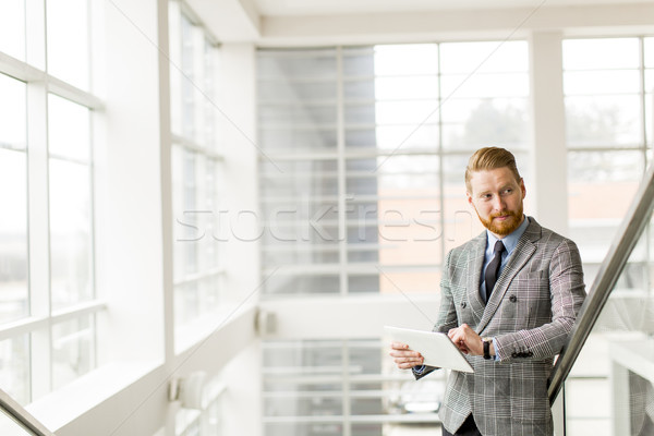 Portrait of young businessman holding digital tablet while stand Stock photo © boggy