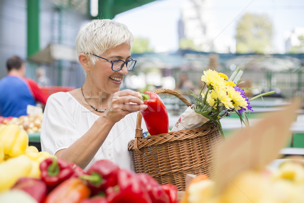Stock photo: Good-looking senior woman wearing glasses buys pepper on market