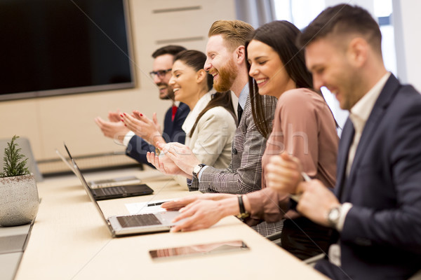 Happy smiling business team clapping hands during a meeting in o Stock photo © boggy