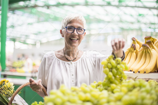 Good-looking senior woman buys bananas at the market Stock photo © boggy