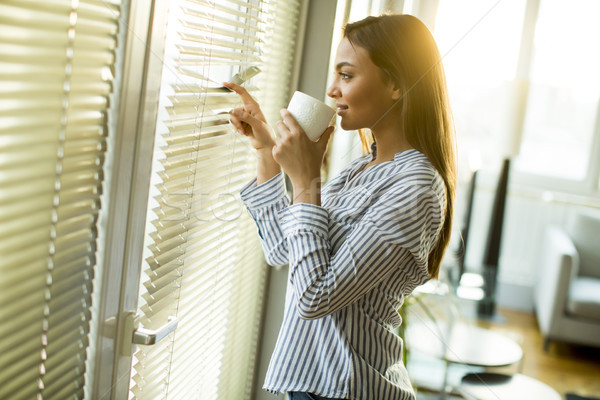Attractive  young woman holding cup with hot tea or coffee and l Stock photo © boggy