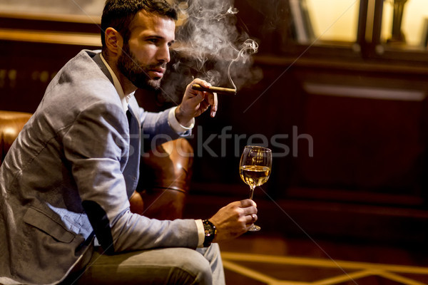 Young man tasting white wine and smoking cigar Stock photo © boggy