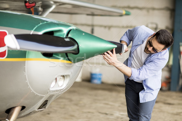 Young pilot checking airplane in the hangar Stock photo © boggy