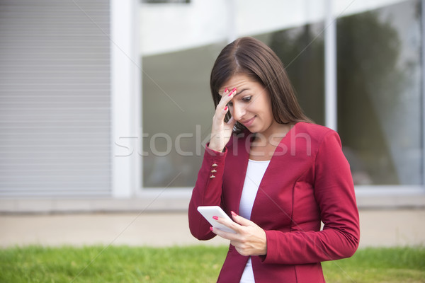 Worried  businesswoman in red blazer using mobile phone outdoor Stock photo © boggy