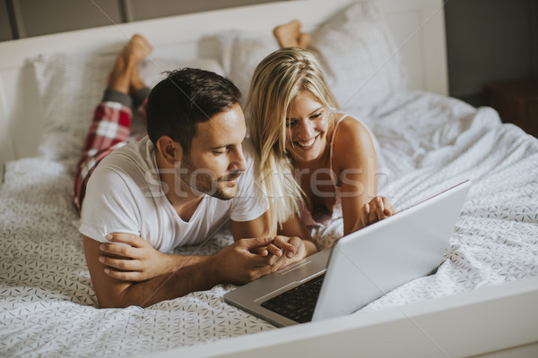 Intimate lovers using laptop lying on the bed Stock photo © boggy