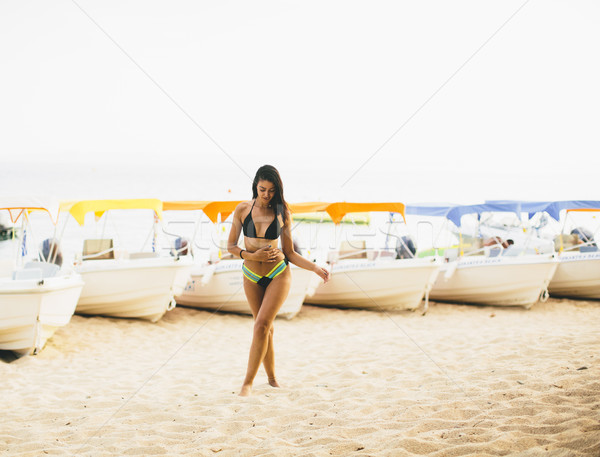 Fit and sporty woman in a swimsuit relaxing on a beach at summer Stock photo © boggy