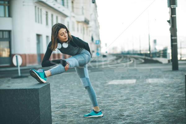Stock photo: Young sportswoman stretching and preparing to run