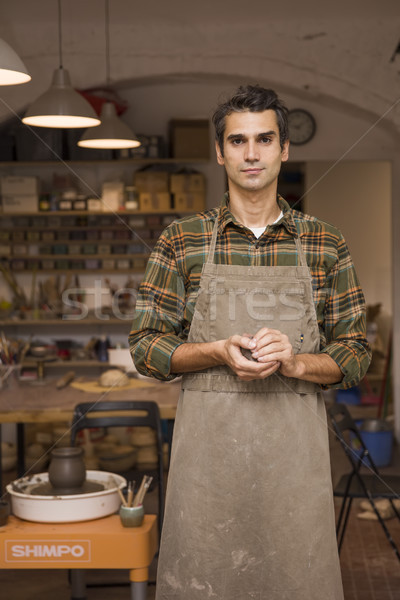 Handsome young man in pottery workshop holding clay Stock photo © boggy