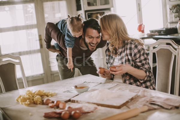 Happy family making pasta in the kitchen at home Stock photo © boggy