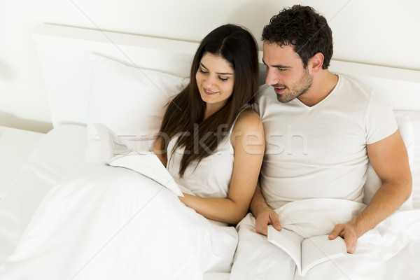 Young couple reading a book in the bed Stock photo © boggy