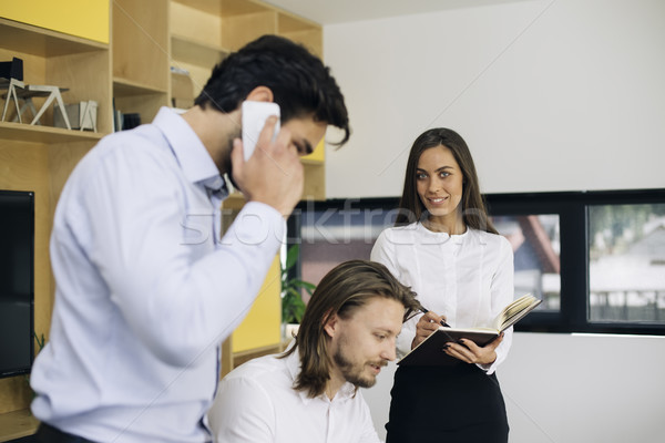 Handsome businessman using mobile phone in the office while othe Stock photo © boggy