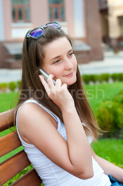 Girl said on his cell sitting on a bench. Stock photo © borysshevchuk