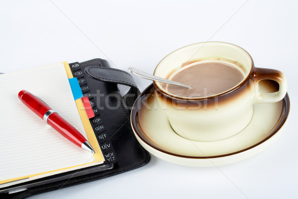 Close-up of a cup of coffee with the spoon inside and notebook with ballpoint Stock photo © broker