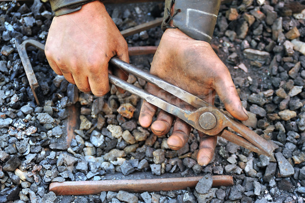 Detail of dirty hands holding pliers - blacksmith Stock photo © brozova