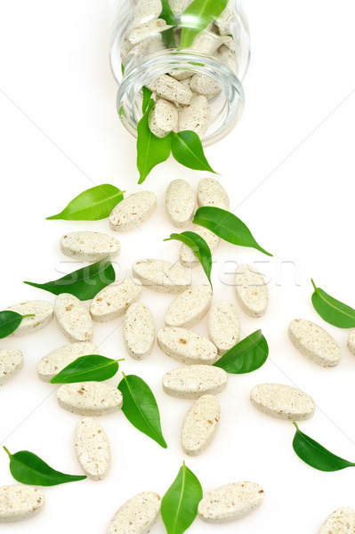 Herbal supplement pills and fresh leaves  spilling out of bottle – alternative medicine concept Stock photo © brozova