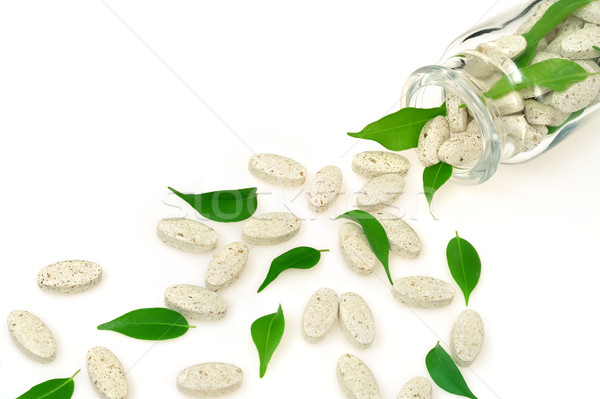 Herbal supplement pills and fresh leaves  spilling out of bottle – alternative medicine concept Stock photo © brozova