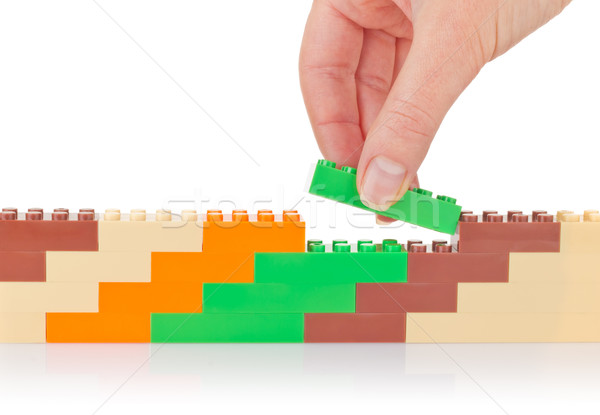 Hand build wall of colour toy block Stock photo © brulove