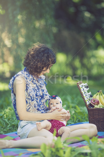 Stock photo: Young mother playing with baby on blanket in the park