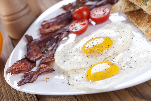 Delicioso huevo frito especias tocino tomates blanco Foto stock © BrunoWeltmann