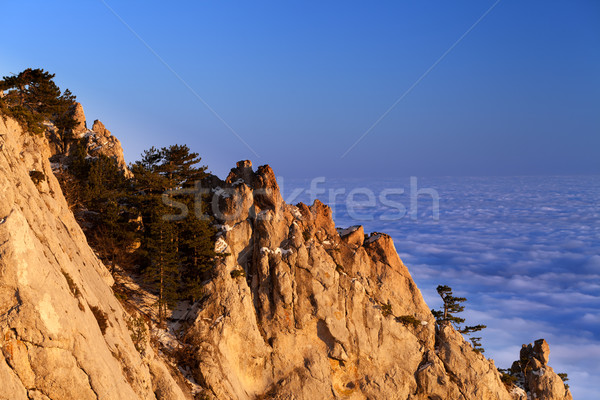 Sunlit rocks and sea in clouds at evening Stock photo © BSANI