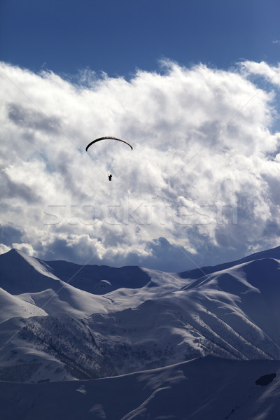 Winter mountain with clouds and silhouette of parachutist Stock photo © BSANI