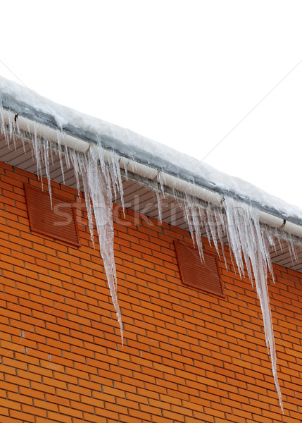 Snow-covered roof with icicles on white background Stock photo © BSANI